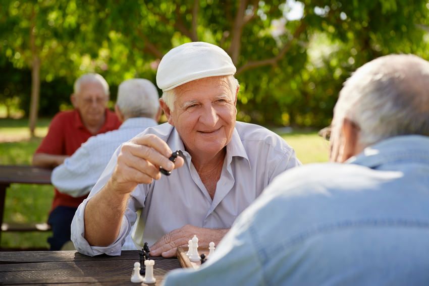 Active retired seniors, two old men playing chess at park