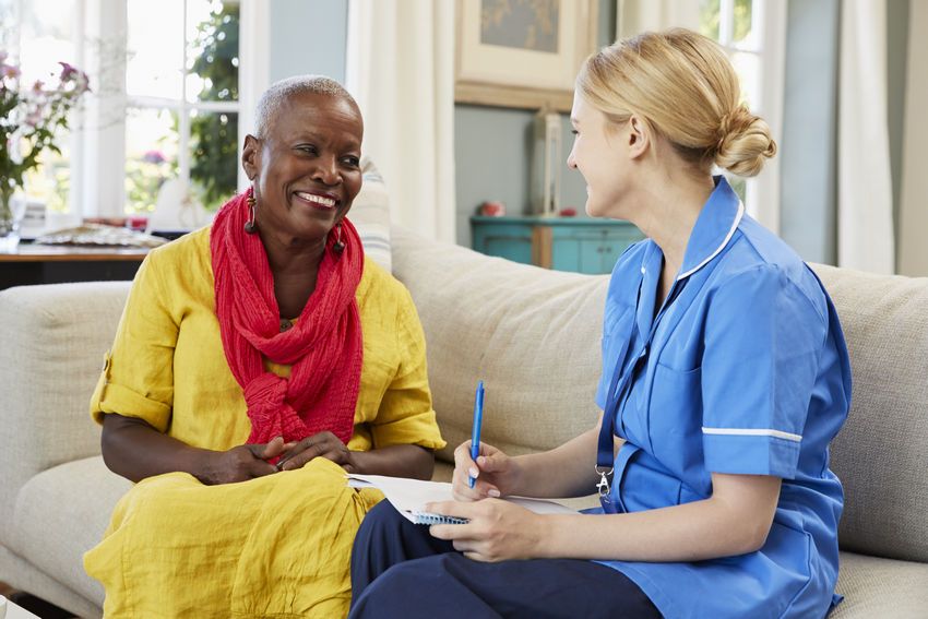 Female Community Nurse Visits Senior Woman At Home