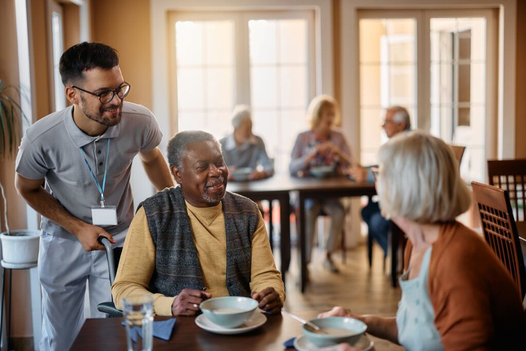 Young healthcare worker and senior people during lunch at nursing home. Senior care services in Harrisburg