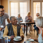 Young healthcare worker and senior people during lunch at nursing home. Senior care services in Harrisburg