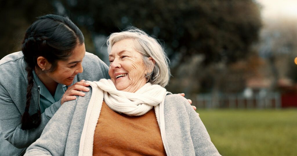 Caregiver helping woman with disability in park for support, trust and care in retirement. Nurse talking to happy senior patient in wheelchair for rehabilitation, therapy and conversation in garden Senior care services in Allentown