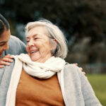 Caregiver helping woman with disability in park for support, trust and care in retirement. Nurse talking to happy senior patient in wheelchair for rehabilitation, therapy and conversation in garden Senior care services in Allentown