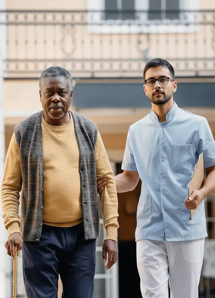 Caregiver assisting elderly man with cane outdoors