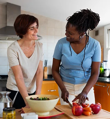 Caregiver helping senior woman prepare healthy meals in home kitchen