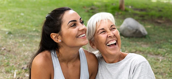 Senior woman and caregiver smiling together outdoors during companionship care visit