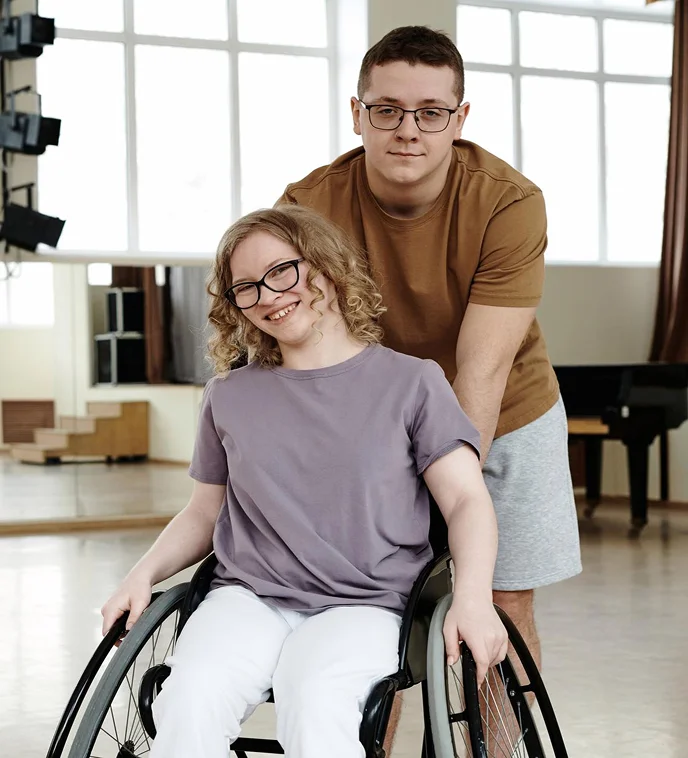 Young man supporting smiling woman in wheelchair during disability care and companionship services