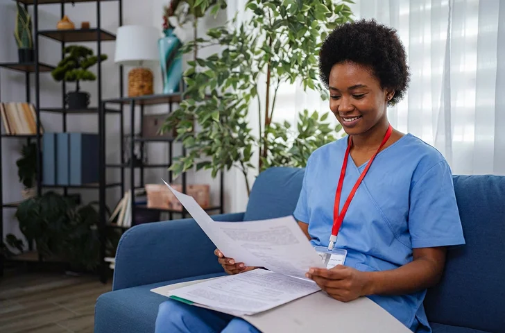 Professional home healthcare nurse reviewing patient documents during in-home visit