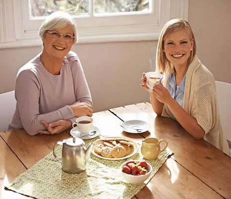 Senior woman and caregiver enjoying tea and conversation during in-home senior care visit