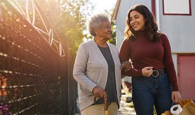 Young woman assisting elderly family member with walking support and grocery shopping outdoors