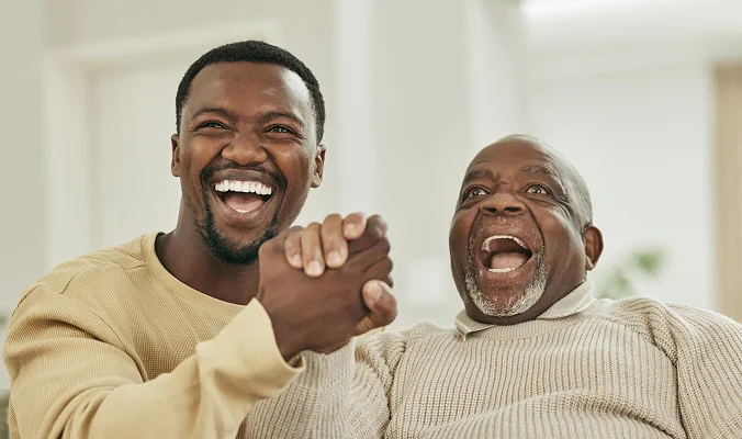 Happy senior man and caregiver celebrating joyful companionship and emotional support at home