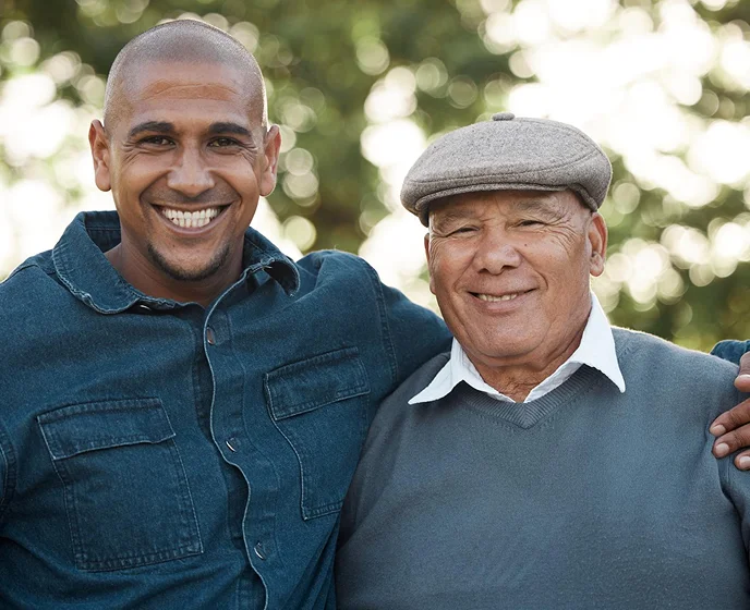 Adult son and elderly father smiling together during family companionship and senior support