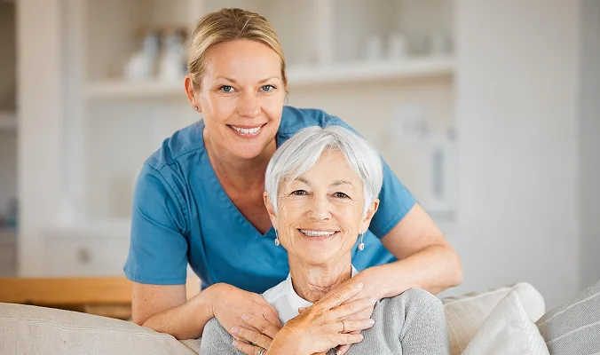 Friendly caregiver and senior woman smiling together during home care assistance