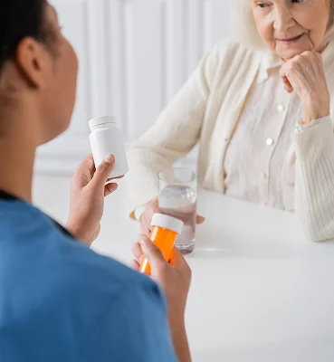 Caregiver explaining medication management to senior woman at home