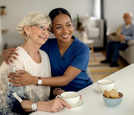 Compassionate caregiver sharing quality time with smiling senior woman during home care visit