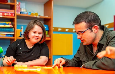 Support worker assisting young woman with developmental disabilities during educational activity
