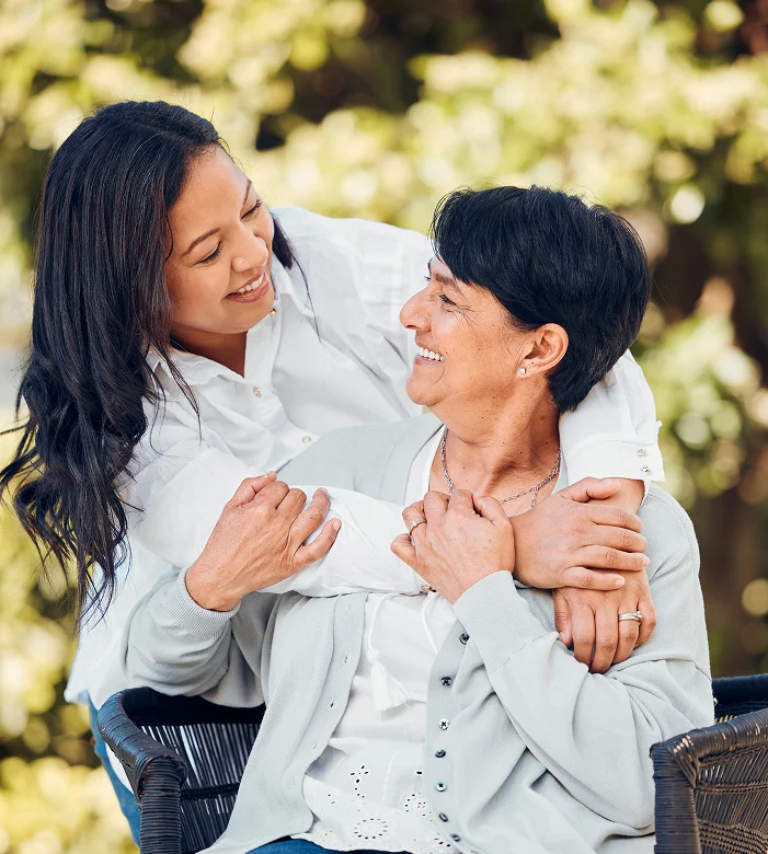Compassionate caregiver embracing smiling senior woman outdoors during home care visit