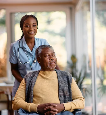 Professional caregiver assisting senior man in wheelchair during home care support
