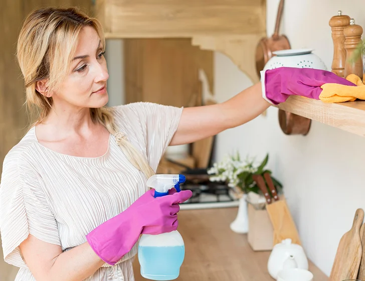 Professional housekeeper cleaning kitchen shelves during residential housekeeping service