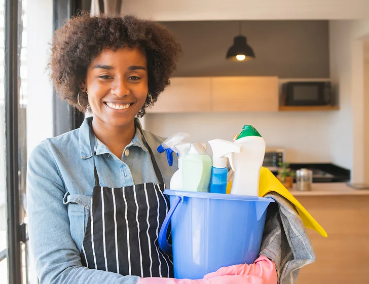 Professional housekeeper holding cleaning supplies for residential home care and housekeeping services