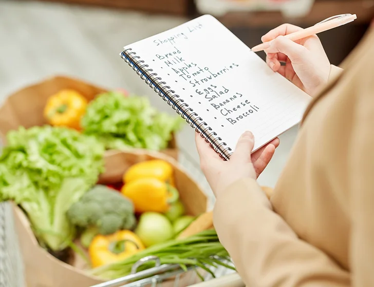 Caregiver preparing a grocery shopping list with fresh produce