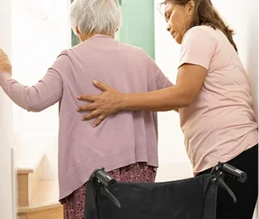 Caregiver reads to senior woman in wheelchair with blanket and tea